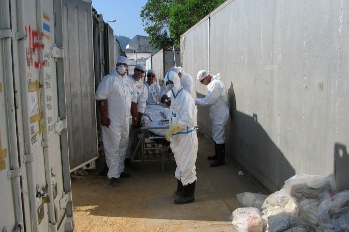 A team transports bodies to and from storage containers in Thailand. Photo/ Bob Hooker.