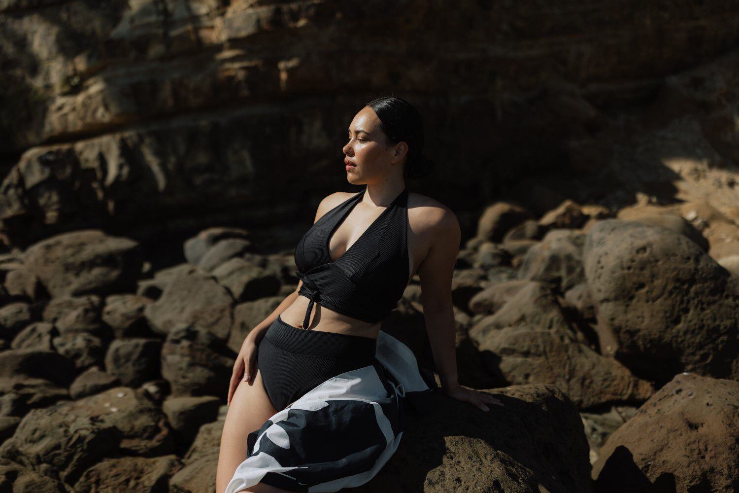 Premium Photo  Model with big breasts in a black swimsuit poses on black  sand beach.