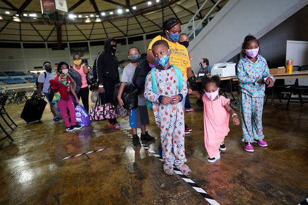 Victoria Nelson with her children Autum Nelson, 2, Shawn Nelson, 7, and Asia Nelson, 6, line up to board a bus to evacuate Lake Charles, Louisiana. Photo / AP