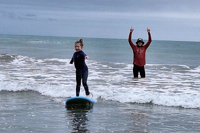 Ollie Dobbin (in the background) teaches Georgia Thornton (6) how to surf on Ōhope Beach. Supplied photo