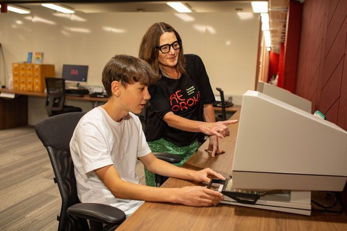 Heritage specialist Jody Smart teaches a student to operate a microfiche machine. Photo: supplied.