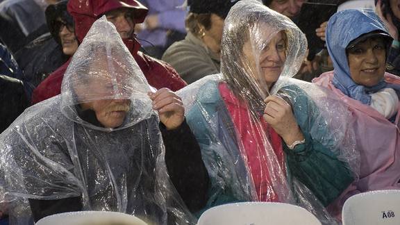 Fans struggle to put on ponchos in rain 