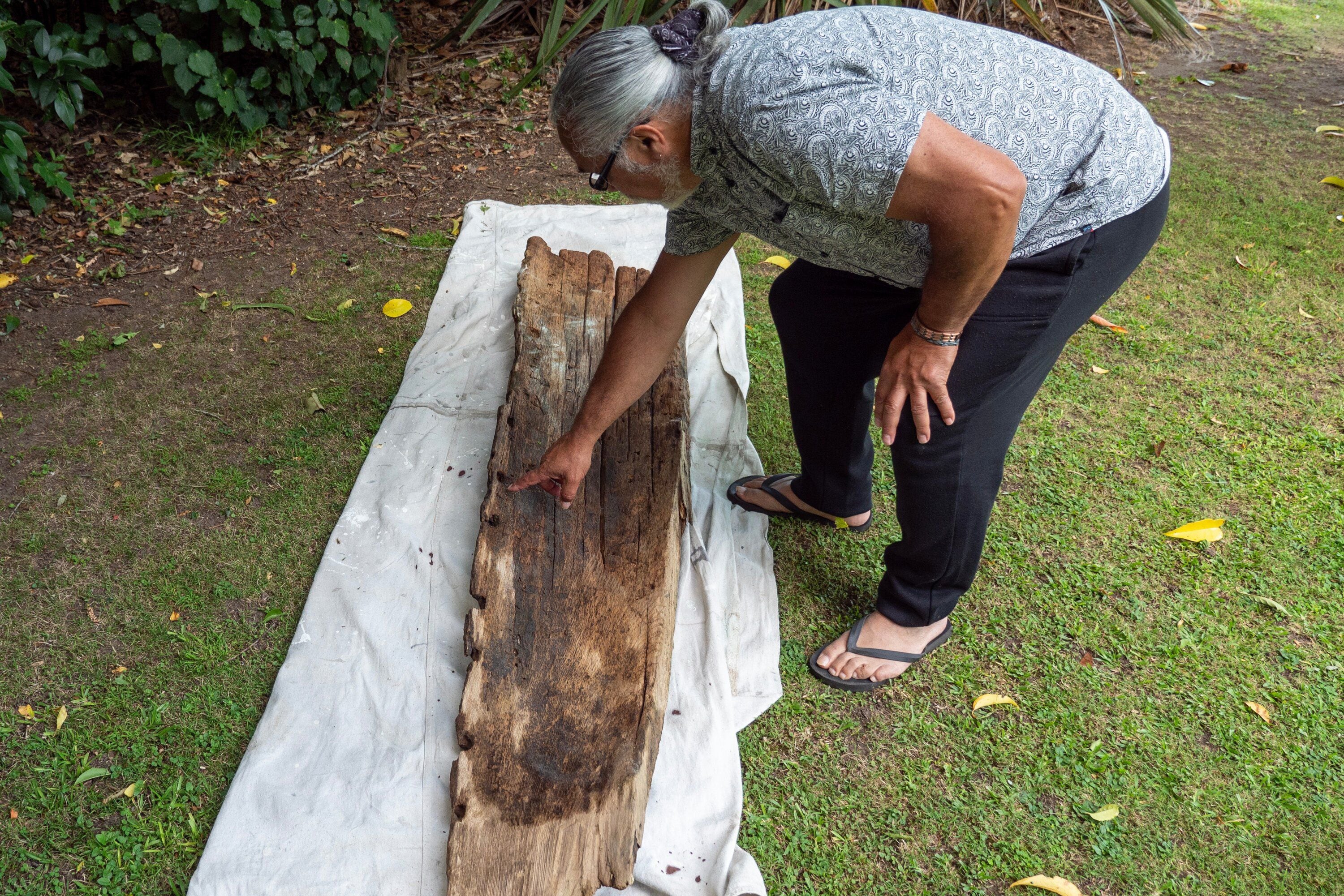 Dean Flavell points out various holes on the waka used for the lashings. He believes that a chisel was used and dates the waka to around the 16 and 17th centuries.