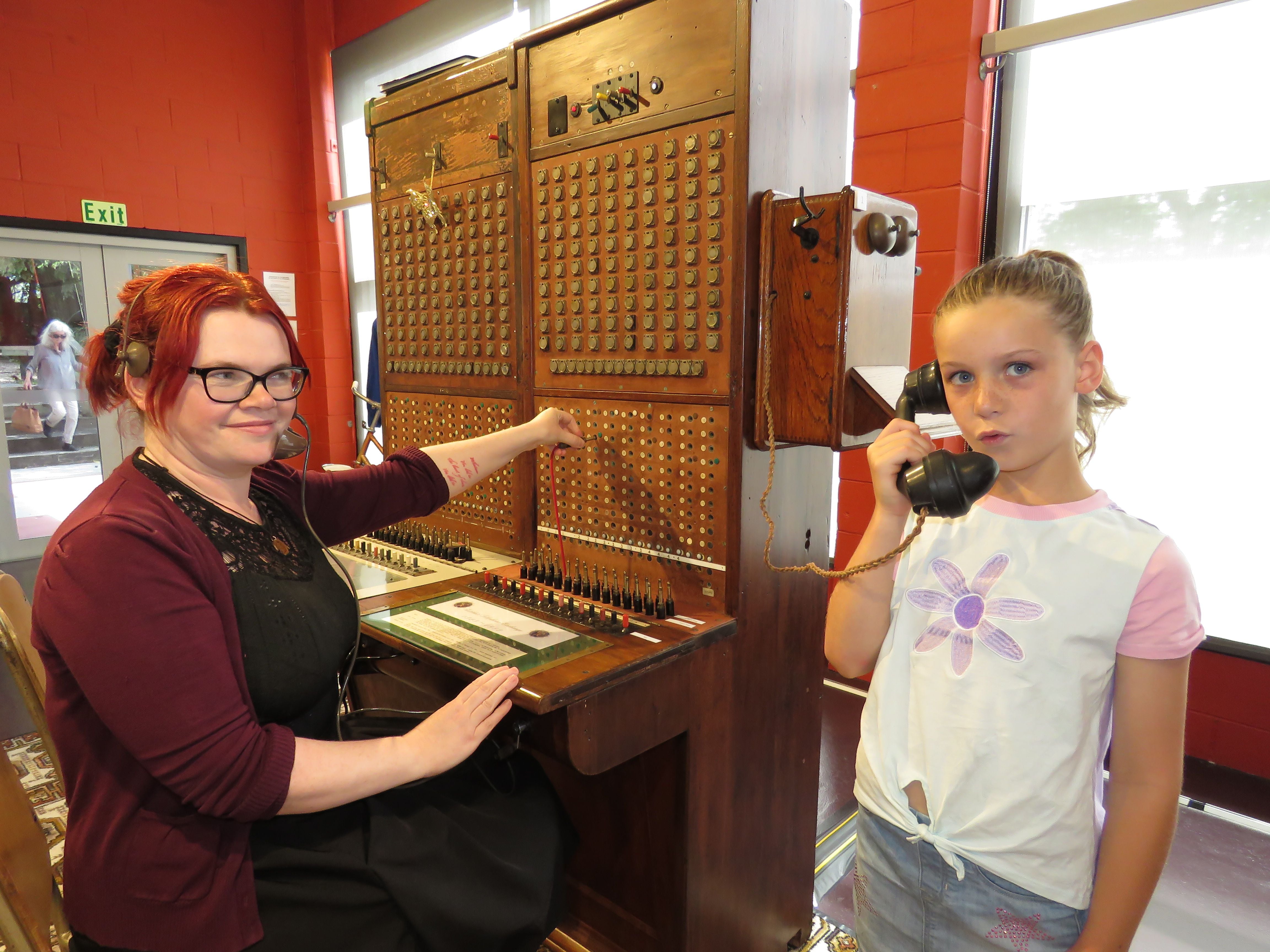 Museum curator Carly Vevers watches on as Eden Cave talks to her sister via the old Katikati Telephone Exchange. Photo: Merle Cave